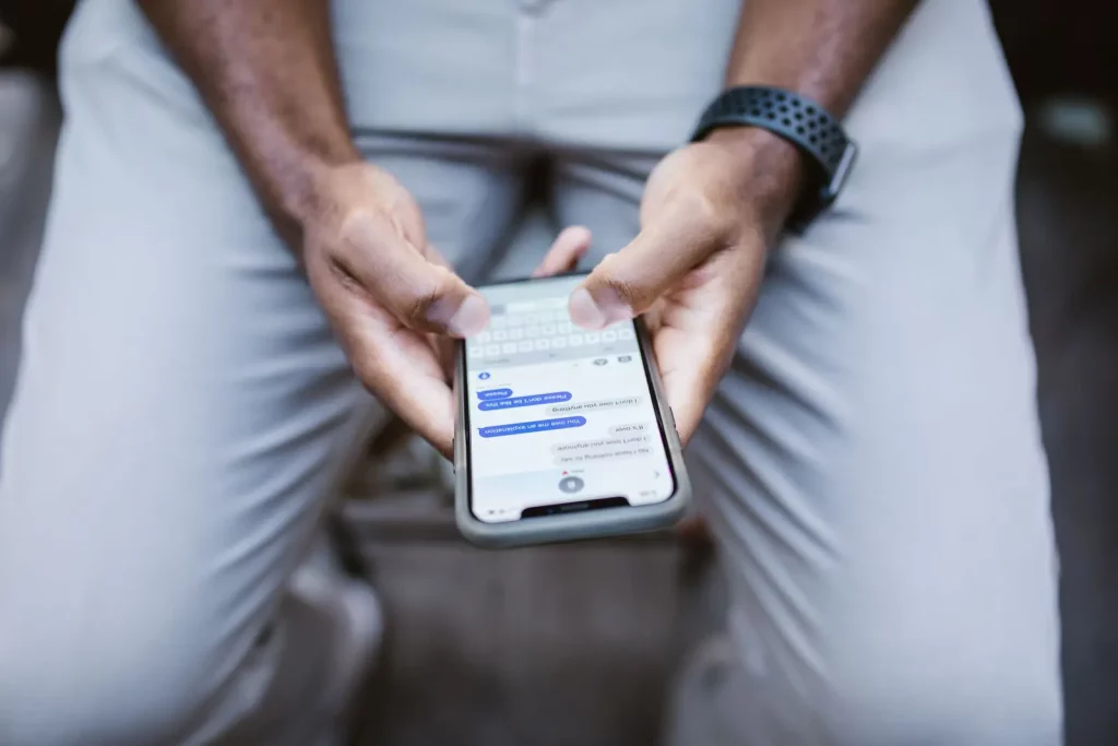 Tangan mengetik pesan di layar smartphone, ilustrasi WhatsApp Business API untuk bisnis yang melayani banyak pelanggan dari banyak agen sekaligus
